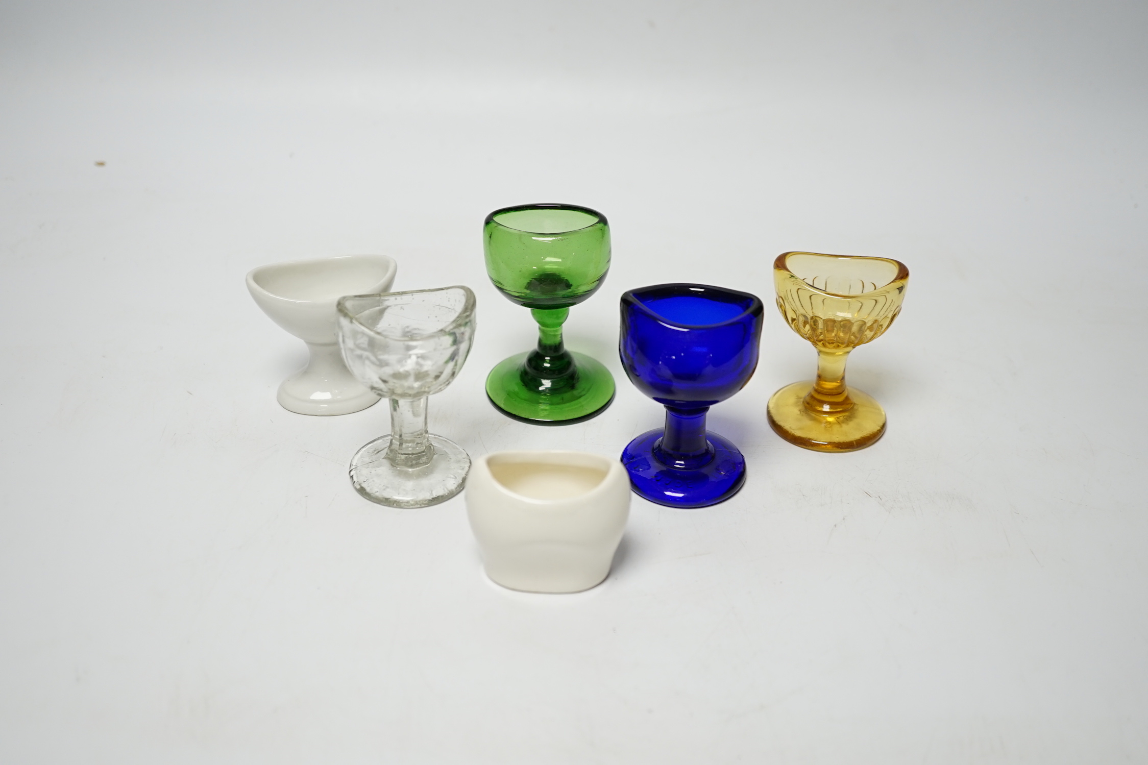 Thirty-four glass and porcelain eye baths, including green and blue glass examples